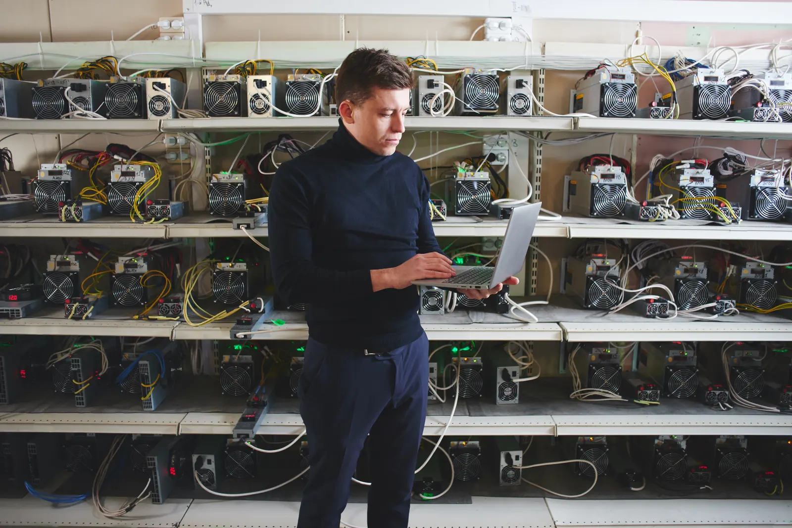 Tehniķis ar planšetdatoru pie plauktiem ar elektronikas ierīcēm